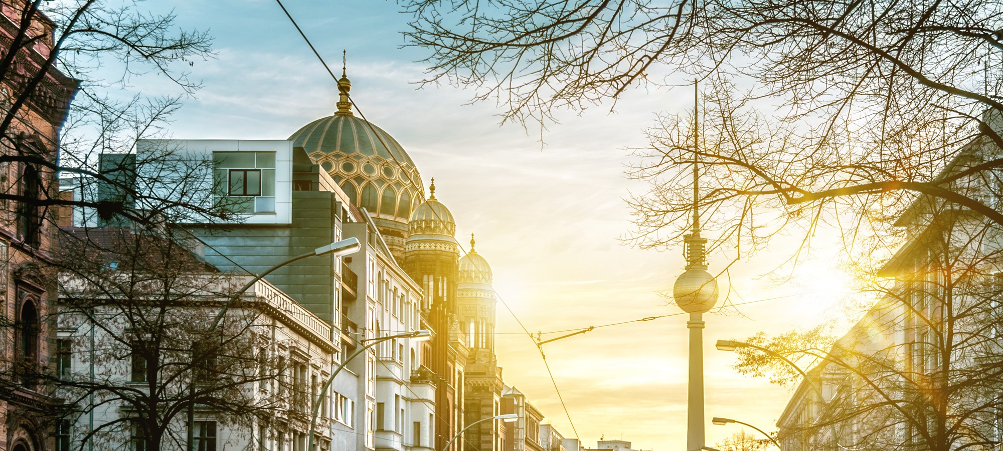 Morgenaufnahme der Oranienburger Straße mit Blick auf die neue Synagoge und den Fernsehturm im Licht der aufgehenden Sonne
